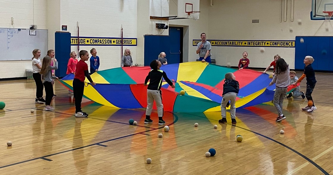 Kids playing with parachute in gym